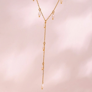Détail d'un collier en Y doré élégant avec perles blanches sur tissu en soie