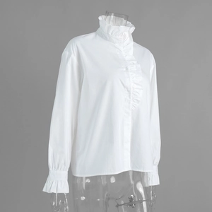 Detail view of the standing collar and ruffles on a white long-sleeve cotton blouse