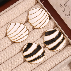 Detailed macro view of two pairs of round textured 18K gold plated enamel stud earrings