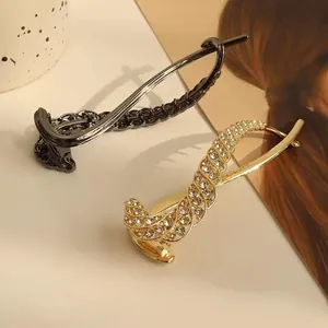 Detail of luxury rhinestone banana hair clip and gunmetal woven hair slide on cream background
