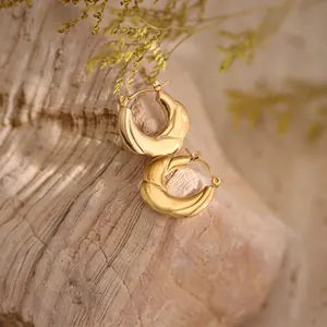 Detail of twisted 18K gold plated stainless steel chunky hoop earrings on stone