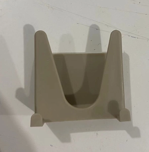 Dettaglio di un supporto a parete beige per coperchi o spugne in materiale plastico opaco