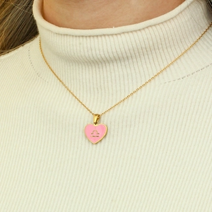 Close-up of gold necklace with pink heart Libra zodiac sign pendant on model