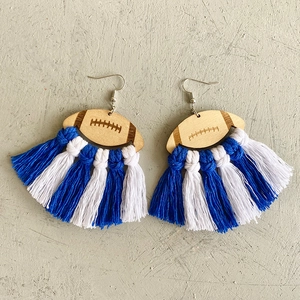 Detailed view of handmade football wooden earrings with blue and white woven cotton tassels