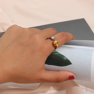 Detail of two-tone gold and silver open ring with teardrop motif on silk