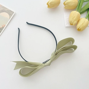 Detail of light green satin bow headband featuring elegant layered silk fabric texture
