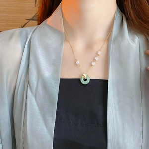 Gros plan du collier ginkgo plaqué or avec pendentif en jade vert et perles blanches