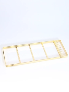 Detail view of golden metal jewelry rack with earring holes and small side hooks