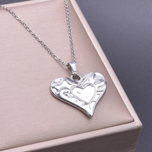Macro shot of silver textured heart pendant on fine chain over a golden jewelry box