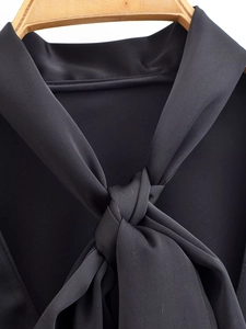 Detail shot of the silky black fabric texture and stylish neck tie-up design on top