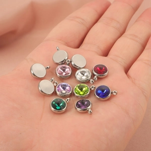 Detailed view of colorful crystal birthstone pendants for DIY jewelry making in a hand