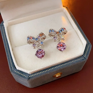 Close-up of silver bow earrings with colorful crystals in a blue velvet jewelry box