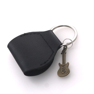 Detail of black leather guitar pick pouch with metal keychain and vintage bronze pendant