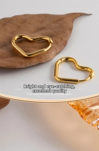 Close-up of gold heart-shaped hoop earrings on elegant dry leaves background