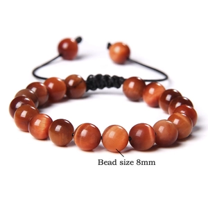 Macro detail of 8mm red tiger eye gemstone beads on adjustable braided cord bracelet