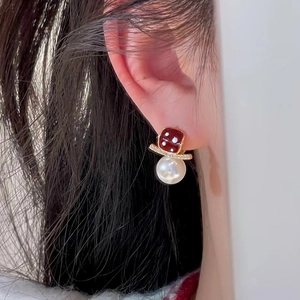 Macro detail of 18K gold plated earring with burgundy dice bead and large pearl drop