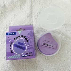 Macro shot of purple comma-shaped makeup puff with SISSIMU ribbon and storage case