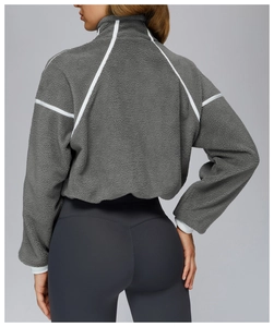 Detail view of deep grey fleece jacket showing white contrast stitching and ribbed cuff