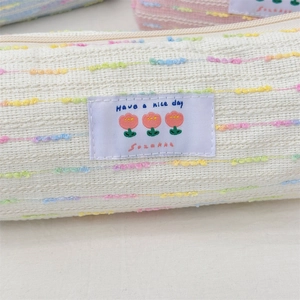Detalle del estuche de tela texturizada con bordado de tulipa y cremallera