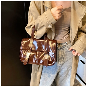 Detail of dark brown glossy leather handbag with double buckles on a vintage messenger bag