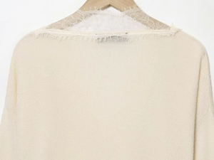 Detailed close-up of cream knit sweater showing delicate white floral lace neckline