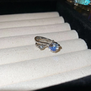 Détail macro d'une bague double en zircone argentée dans un écrin en velours beige