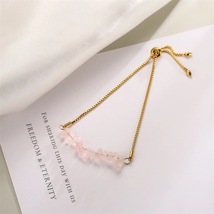 Detailed close-up of pink crystal stone beads on a golden stainless steel chain bracelet