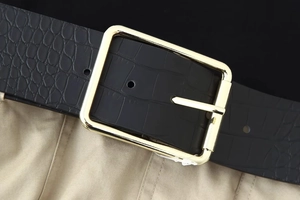 Detail of black crocodile texture leather belt with elegant rectangular gold metal buckle