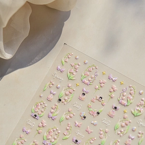 Close-up of 3D embossed lily and bow nail stickers with pearl finish and Spring text