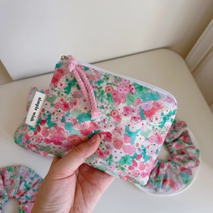 Close-up of pink floral cotton zipper pouch with simple wish label and matching hair tie