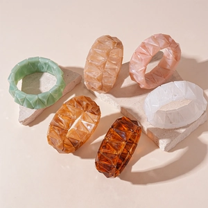 Retro geometric acrylic bracelets in assorted colors on stone pedestal base