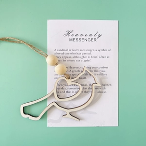 Detail view of a cardinal wooden bird pendant with hanging twine and a message card