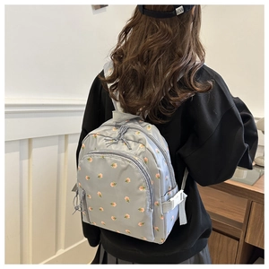 Light grey backpack with pink floral print worn by a model in a bright room