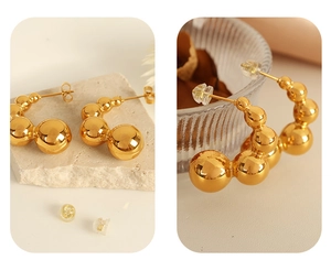 Macro detail of gold graduated bead hoop earrings displayed on elegant natural stone