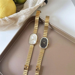 Detailed macro view of vintage oval quartz watches with gold textured straps in a tray