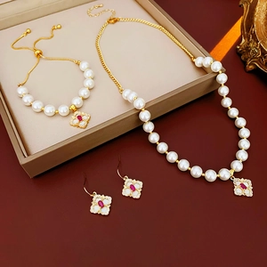 Detail of luxury gold flower clover jewelry set with white pearls and red gemstones