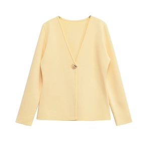 Detail of light yellow knit cardigan featuring a V-neck and a golden decorative button