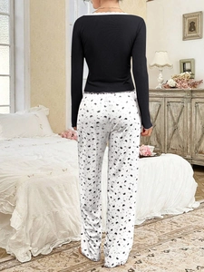 Rear view of long sleeve pajama set with lace V-neck and crown print pants in a bedroom