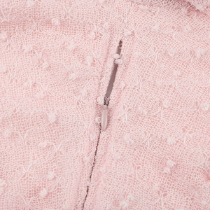 Détail de la fermeture éclair invisible sur une robe en dentelle rose avec maille