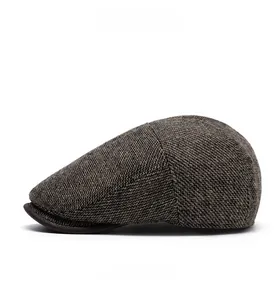 Detail view of newsboy cap showing grey-brown textured fabric and leather brim trim
