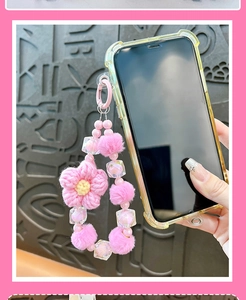 Simpatico cinturino per telefono con fiore rosa all'uncinetto e pompon di peluche