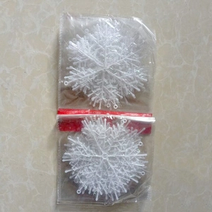 Detailed view of white plastic snowflake decorations with hanging loops in bulk packaging