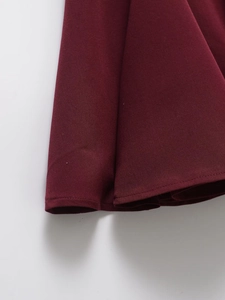 Close-up of wine red flared dress hem showing fine twill fabric texture and stitching