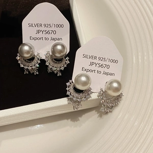 Detail of silver drop earrings with large pearls and sparkling rhinestone tassels