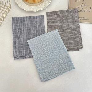 Dettaglio di tovagliette in cotone e lino con strisce blu e motivi a quadretti per la tavola