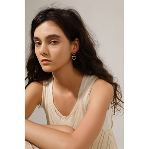 Close-up of double layered gold heart dangle earrings worn by a model