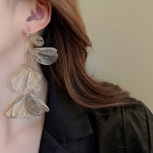 Macro shot of silver oversized petal earrings with hollow metallic mesh texture on model