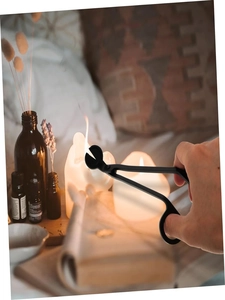 Detail view of black candle wick trimmer in use for home aromatherapy maintenance.