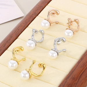 Detail showing gold, silver, and rose gold irregular pearl earrings on a display stand