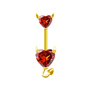 Gros plan du piercing de nombril doré avec cœur en zircon rouge et cornes de démon